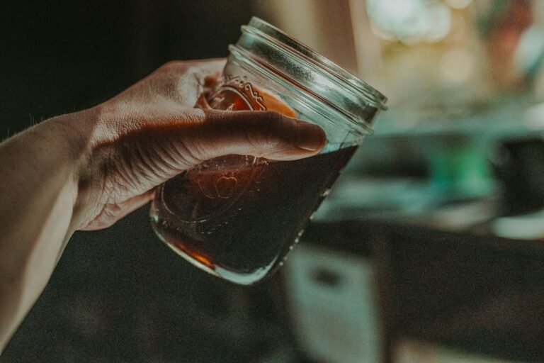 Hand hält ein Einmachglas mit kalt gebrühtem Kaffee