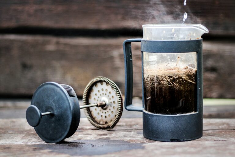 French Press mit frisch aufgegossenem Kaffee, daneben der herausgenommene Pressstempel