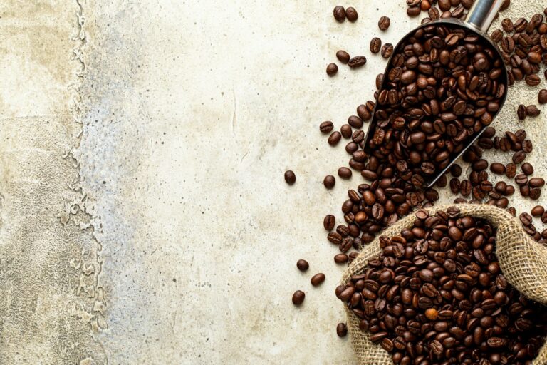 Geröstete Kaffeebohnen in einer Metallschaufel neben einem Jutesack