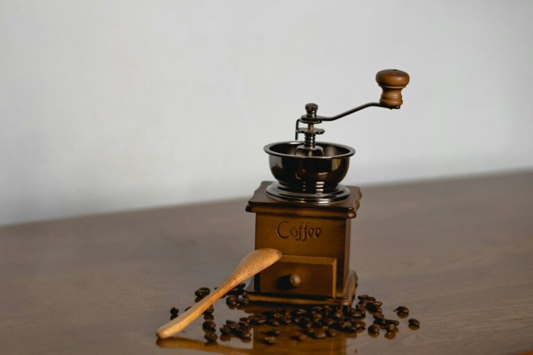 Manuelle Kaffeemühle mit Kaffeebohnen und Holzlöffel