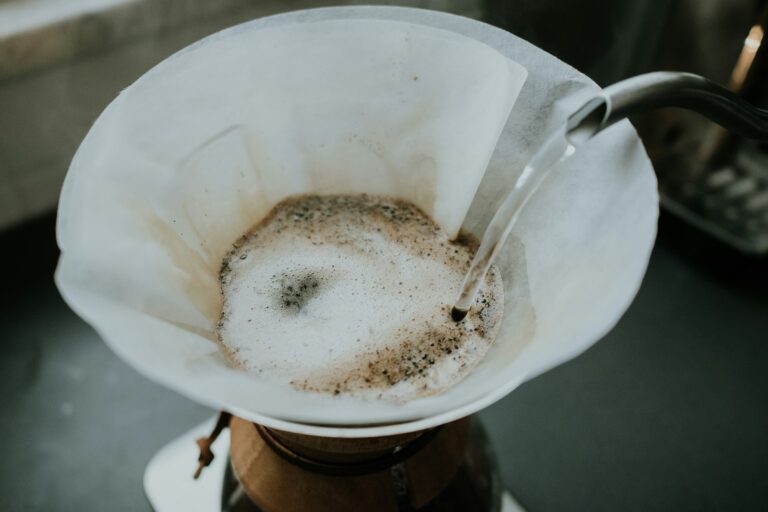 Heißes Wasser wird in einen weißen Papier-Kaffeefilter gegossen